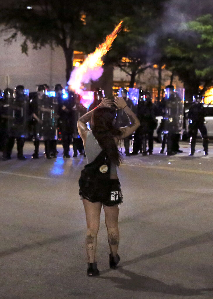 A protester stands with hands raised in front of riot police Monday in St. Louis